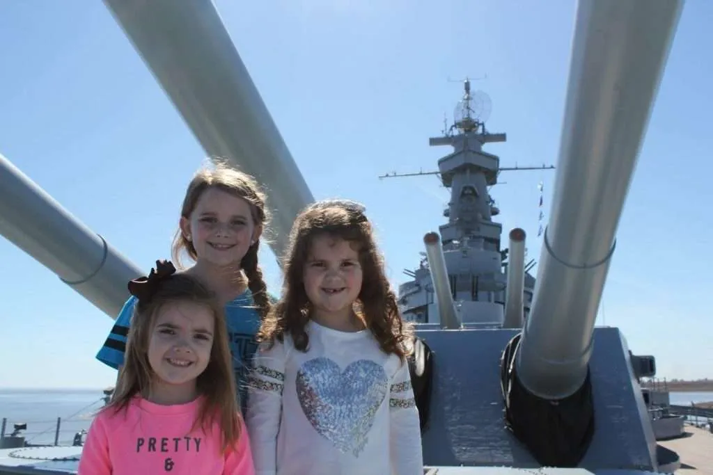 girls in front of USS Alabama mast and guns