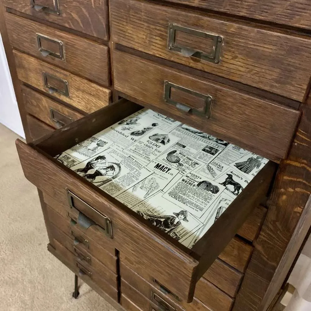 We used vintage newspaper peel and stick wallpaper to line the drawers of the vintage hardware cabinet.