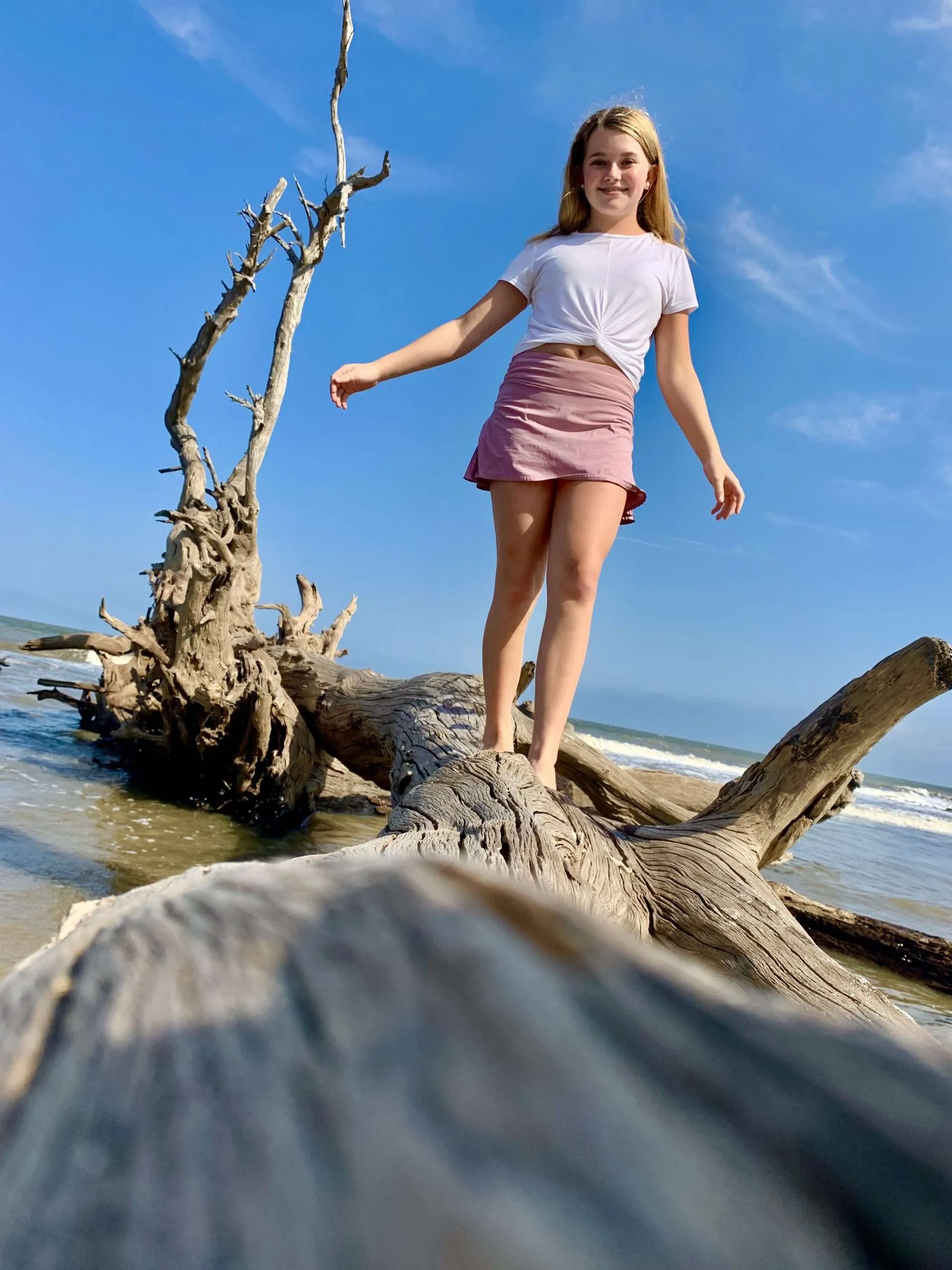 Girl walking on fallen tree at Driftwood Beach, Jekyll Island, Georgia.