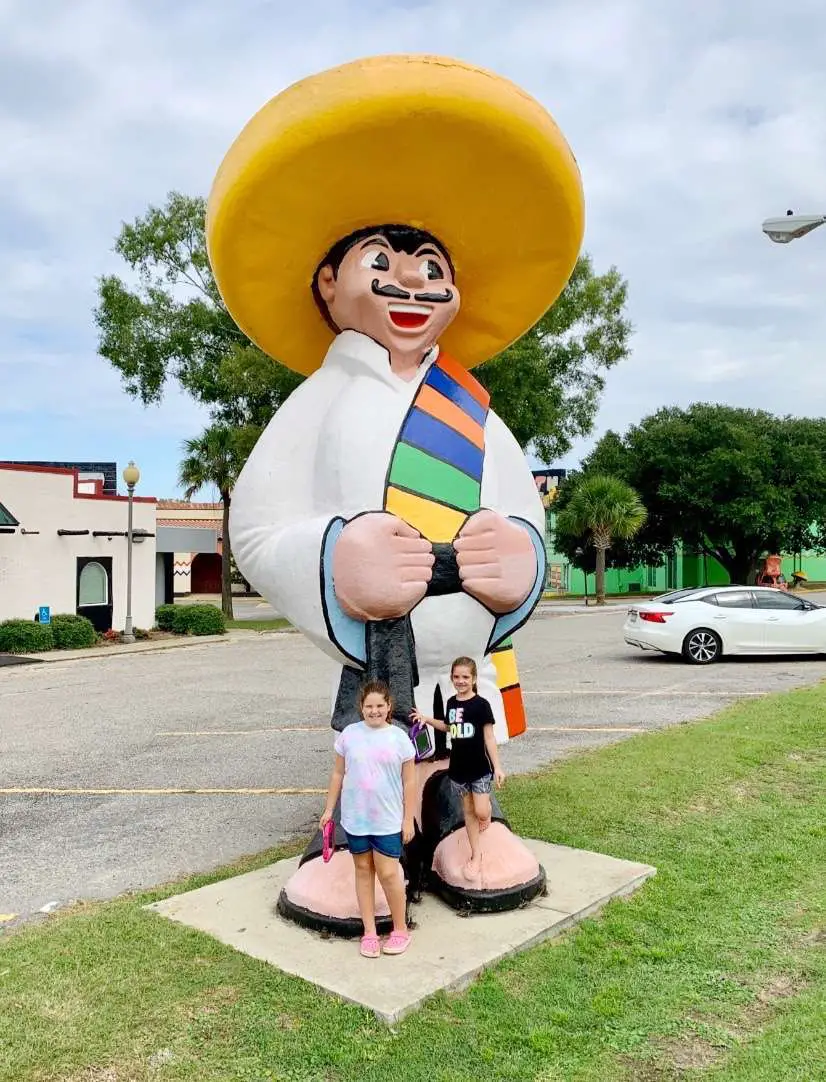 Girls posing with Pedro statue at South of the Border roadside attraction in South Carolina.