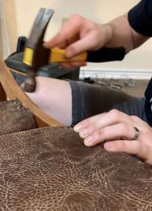 Adding upholstery tacks to our refurbished antique rocking chair.