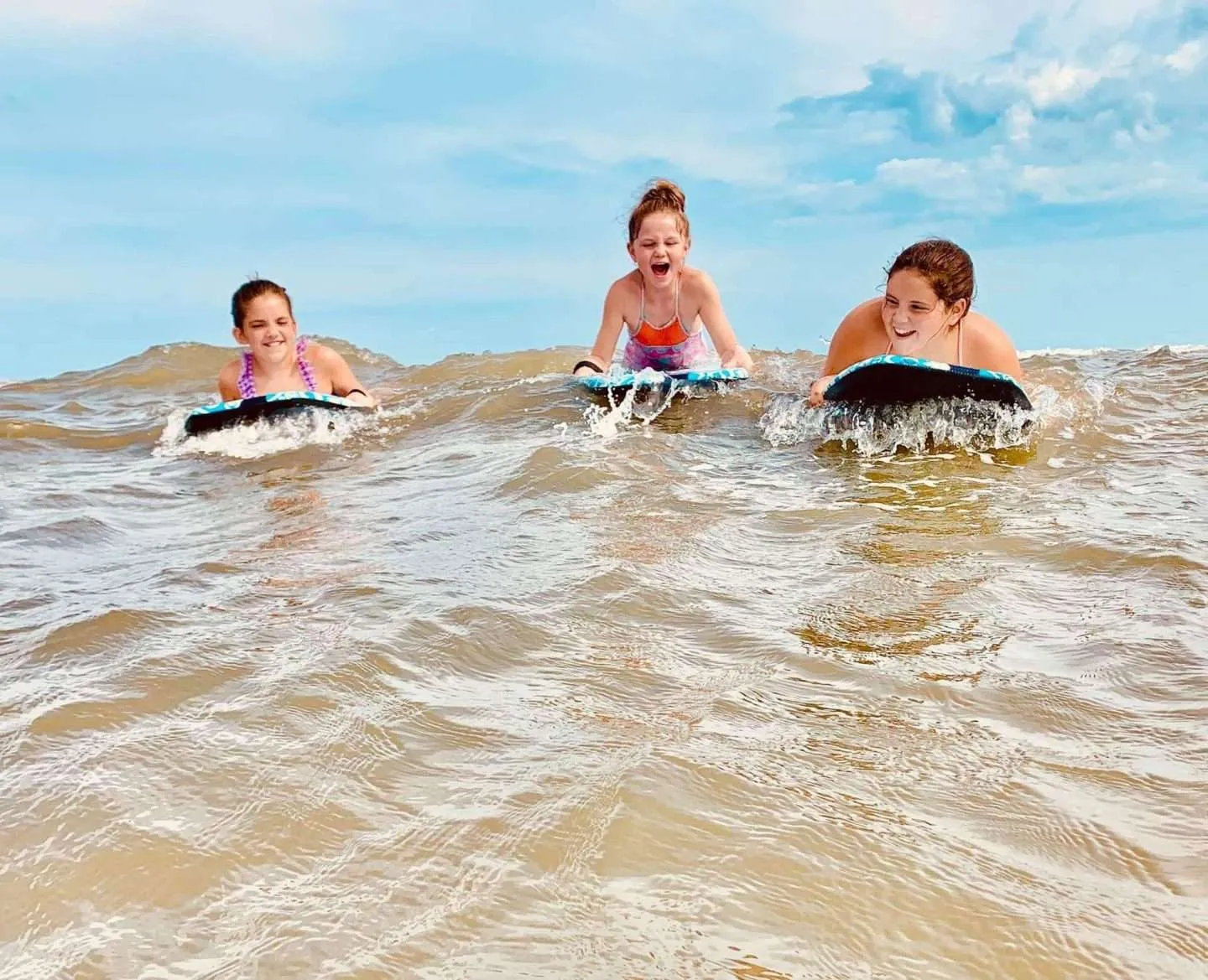 Girls riding boogie boards at a Texas beach. A summer adventure.