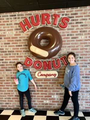 girls in front of Hurts Donuts sign