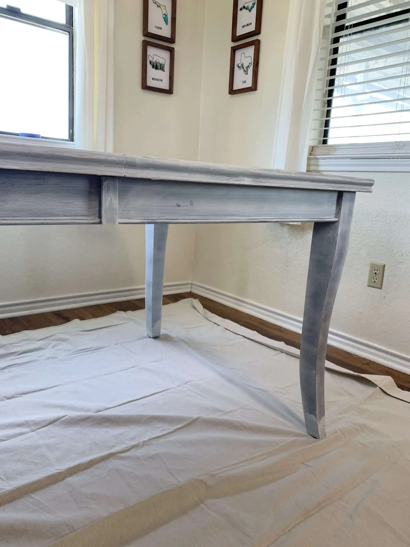 Painting a dining room table after one coat of primer.