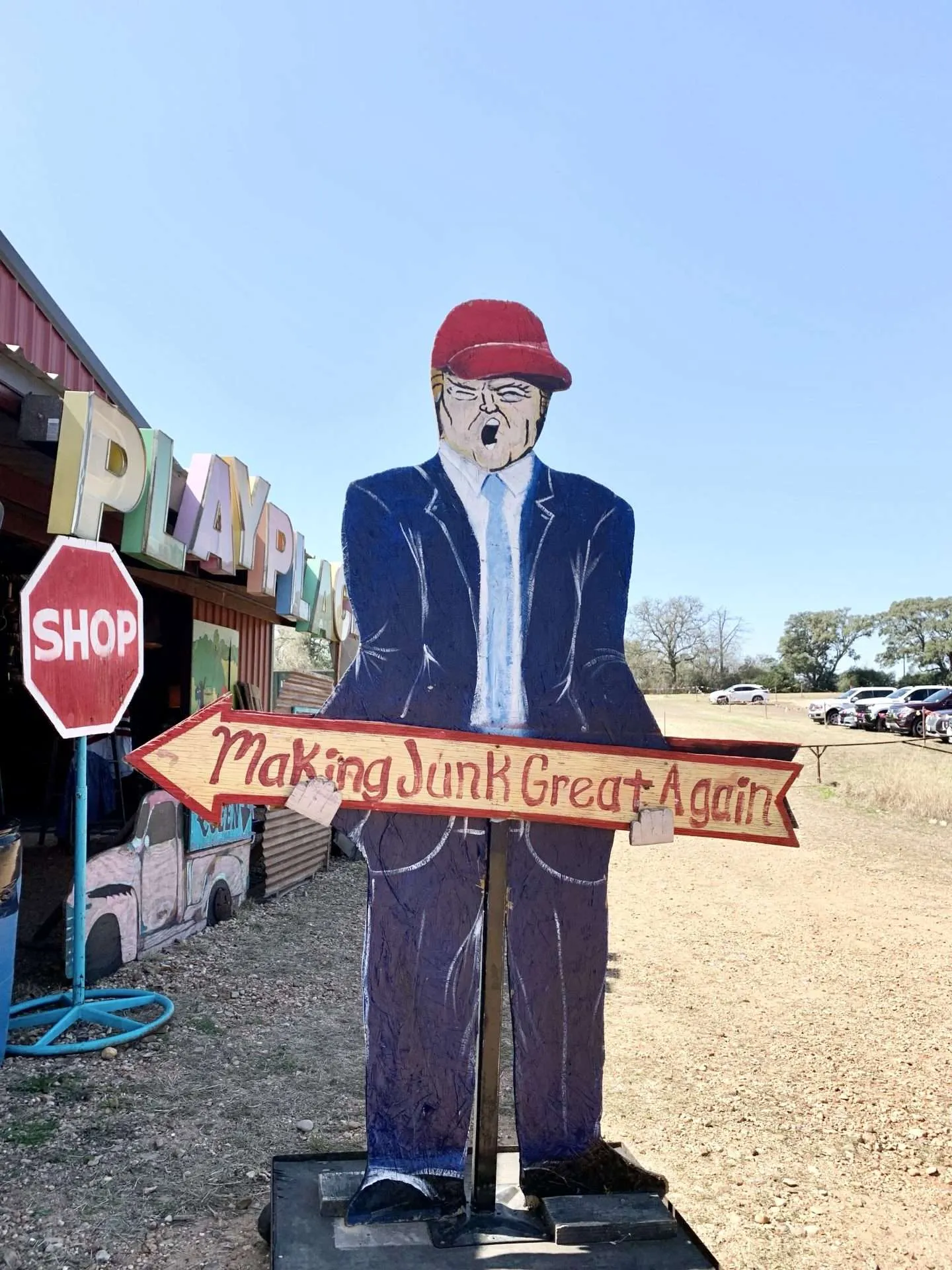 Donald Trump holding a sign that says "Make Junk Great Again!" in Warrenton during the Round Top Antique Show.